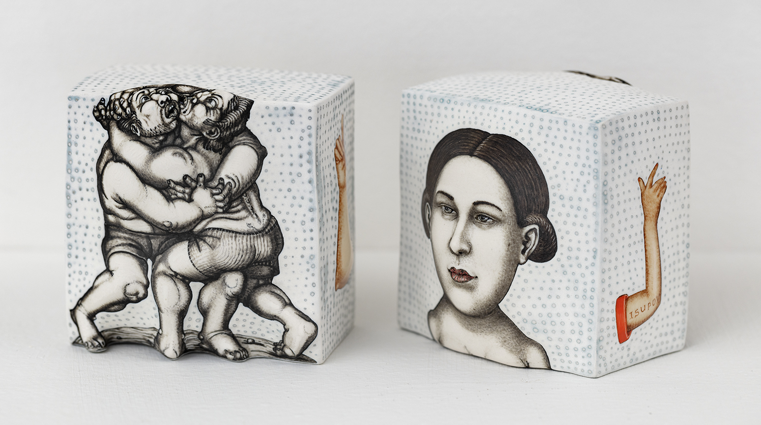Sergei Isupov, "Principle", 2023, porcelain, glaze, 3.5 x 3.5 x 3.5 each - group of two works from the Principle series of Isupov Small Works, both shaped like imperfect pillow cubes, one including a drawing of fight between two men, the other with a drawing of a woman's face, both including depictions of arms on the sides